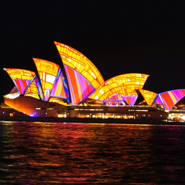 a boat that is lit up at night with Sydney Opera House in the background